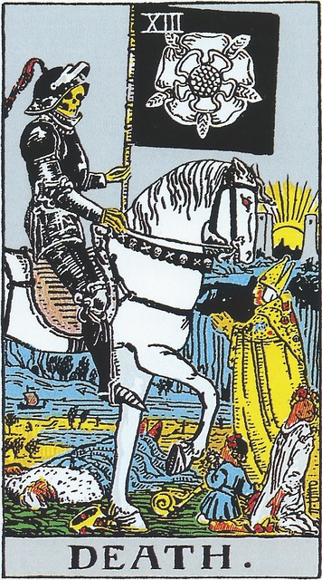 Tarot cards Death
A figure in black armor, face that of a skeleton, rides a white horse with glowing red eyes. A red feather wilts from the peak of his helm. The chest stall of the horse is decorated with skull and crossbones. In his left hand is a black standard bearing the image of a white flower and five ears of corn, or wheat. There is a king lying dead beneath the hooves of his horse, his crown fallen to the ground, and his scepter lying next to him. The land is barren, there is a tiny ship on the seas in the distance. On the ground is a baby in blue, and a maiden in white, both kneeling in supplication. At the head of the horse stands a pope, hands clasped in prayer, with dark shadows stretching out from him. In the distance we see two towers, with the sun setting or rising between them